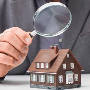 Person holds a magnifying glass over a model home